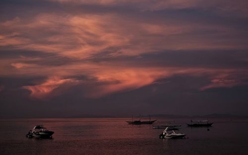 Boats sailing on sea against sky during sunset