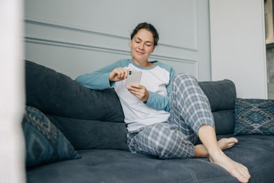 Portrait of young woman sitting on sofa at home