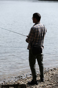 Rear view of man fishing at river