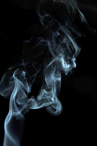 Close-up of burning candle against black background