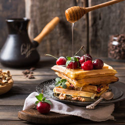 Close-up of honey dipper over breakfast in plate on table