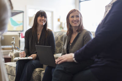 Happy female customers discussing with saleswomen in furniture store