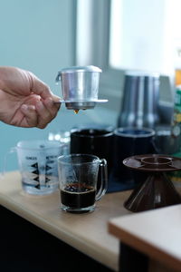 Close-up of hand holding coffee cup on table