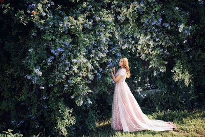 Woman standing by tree against plants