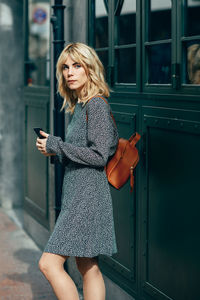 Young woman with mobile phone while standing on footpath