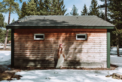 Full length of woman standing by building during winter