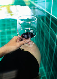 Midsection of person holding drink in swimming pool