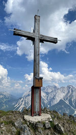 Low angle view of cross on mountain against sky