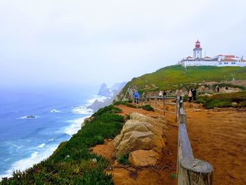 Lighthouse on beach against sky