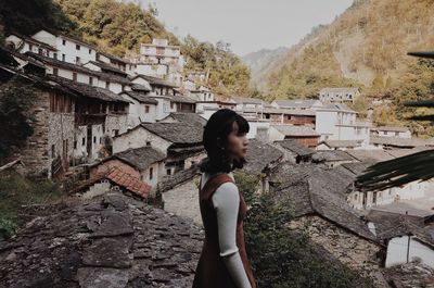 Side view of woman standing against buildings