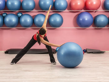Full length of woman exercising with fitness ball on floor
