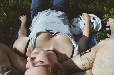 Woman lying down on man legs over field