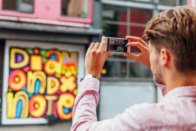 Close-up of man photographing with mobile phone in city