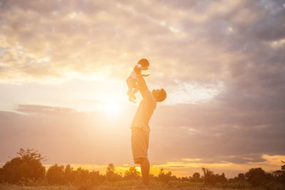 Side view of man standing against sky during sunset