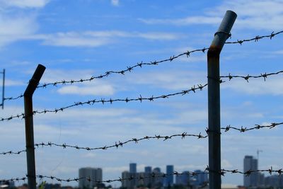 Low angle view of barbed wire fence against sky