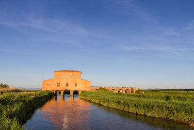 Castle by lake against blue sky