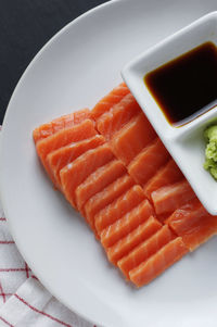 Directly above shot of salmon sashimi with soy sauce served in plate