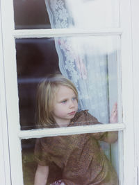 Girl looking through window, smaland, sweden