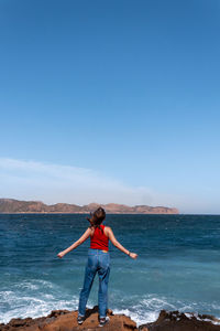 Woman standing on beach against blue sky