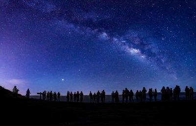 Group of people on field against sky at night