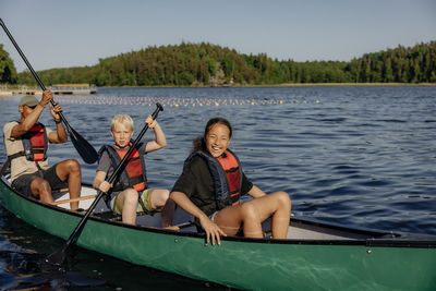 Kids enjoying while doing kayaking with counselors on lake at summer camp