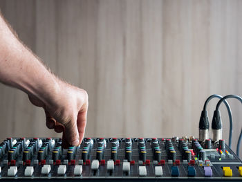 Cropped hand of male dj playing music on sound mixer against wall