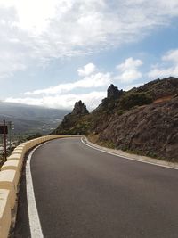 Road leading towards mountains against sky