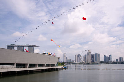 City buildings by river against sky