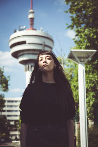 Young woman standing against buildings in city