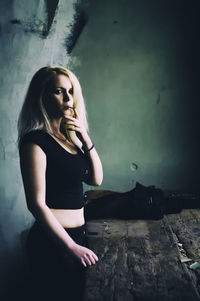 Portrait of young woman smoking while standing in abandoned house