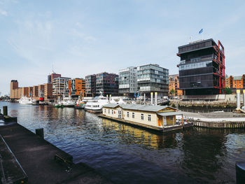 Boats moored at harbor against buildings in city