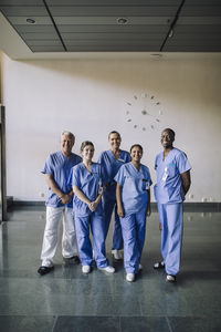 Portrait of smiling diverse healthcare team in blue scrubs standing together at hospital