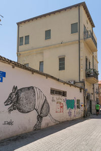 Graffiti on wall by building against sky