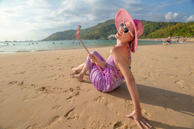 Happy woman sitting on sand at beach