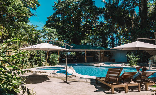 Chairs by swimming pool against clear blue sky