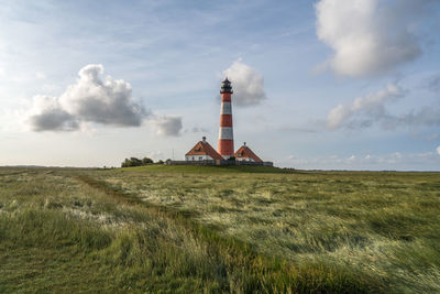 Lighthouse on field against sky