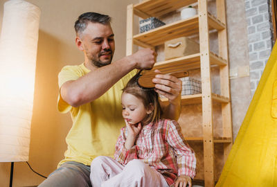 Father holding baby sitting on wooden floor