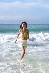 Side view of woman standing at beach against sky