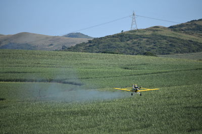 Airplane over field against sky