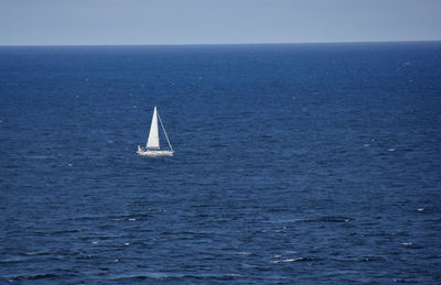 Sailboat sailing in sea against clear sky