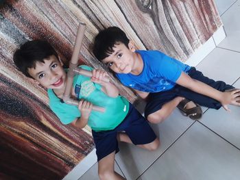 High angle view portrait of siblings smiling on floor