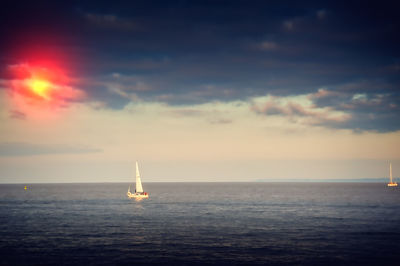 Sailboat sailing on sea against sky during sunset