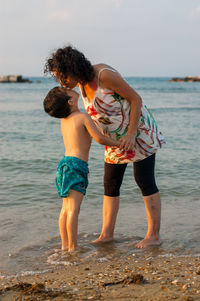 Mother kissing son while standing on beach