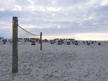 Wooden posts on beach against sky during sunset