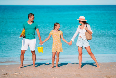 Full length of cheerful family standing on beach