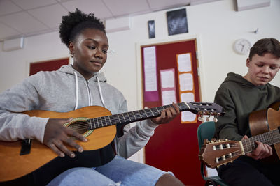 Teenagers attending guitar lesson