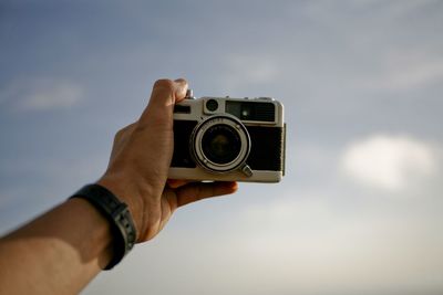 Midsection of men holding camera against sky