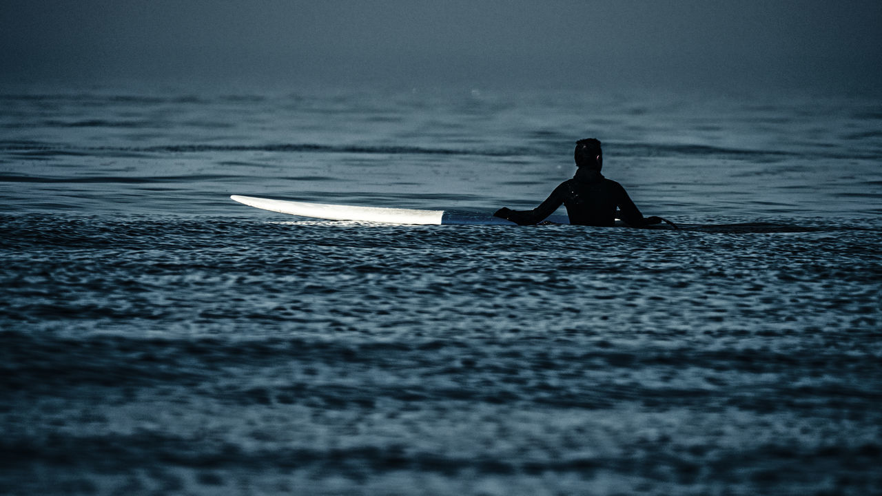 SILHOUETTE MAN ON SHORE AGAINST SKY