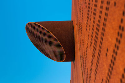 Low angle view of air duct on building against clear blue sky