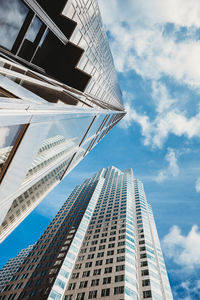 Low angle view of modern buildings against cloudy sky